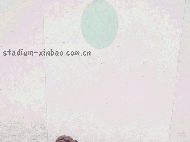 夜间看台上翻开的赛程手册，纸面被暖橙灯光照亮